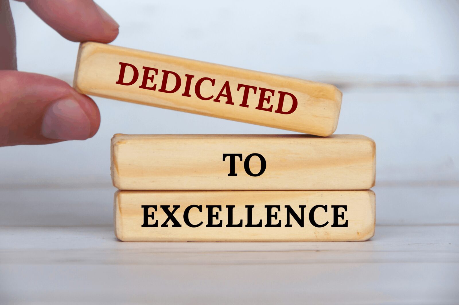 Wooden blocks stacked to read dedicated to excellence