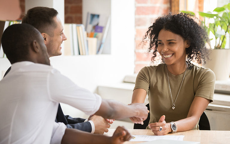 Two professionals shake hands during a meeting about transitioning to a new training package.