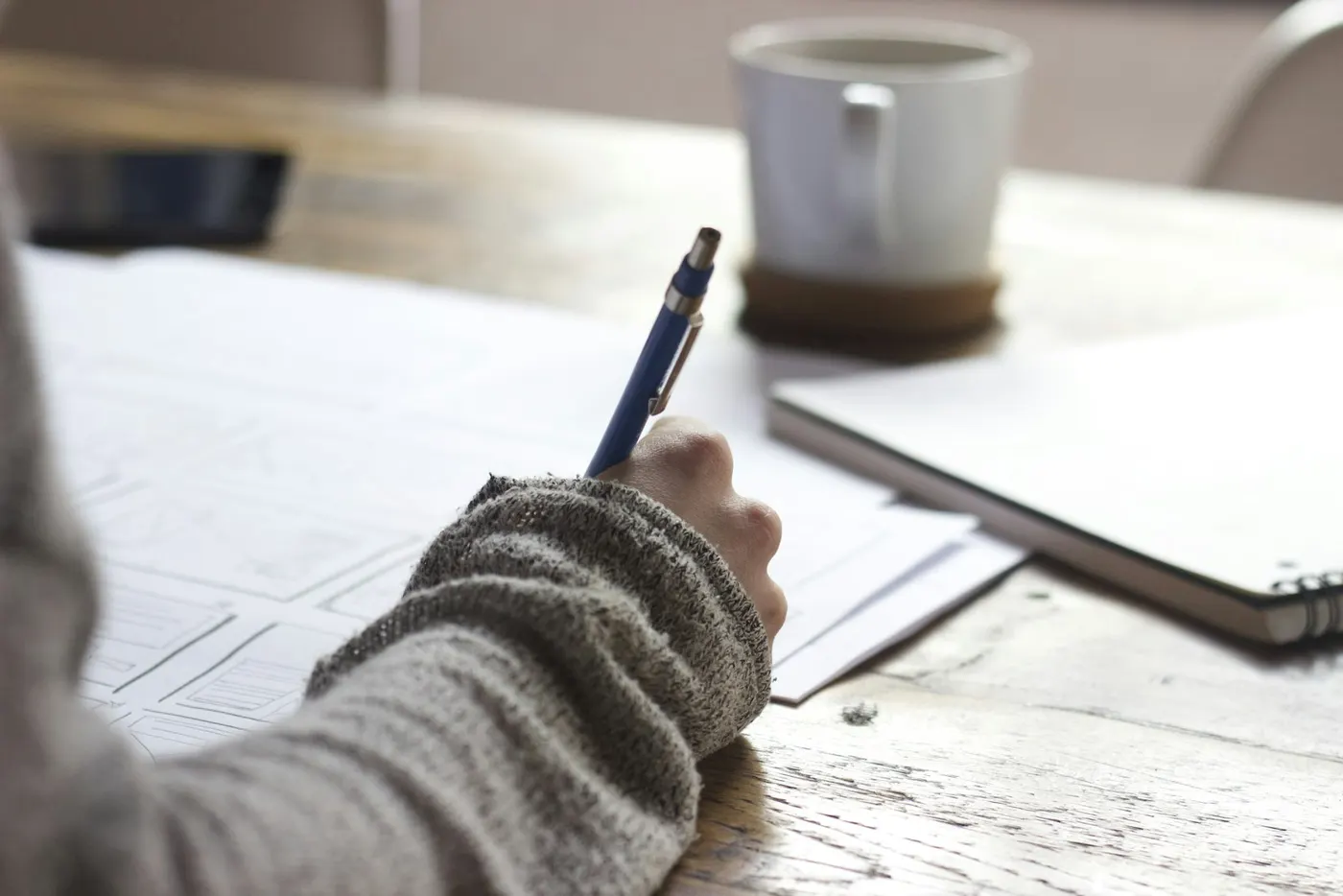 Writing | Career Calling International A person writes on paper with a pen while enjoying coffee, illustrating vocational education training.