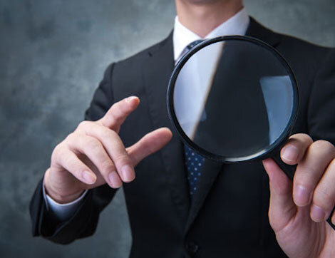 A businessperson examines evidence with a magnifying glass, supporting quality vet compliance.
