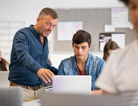 A teacher working with a student at a laptop