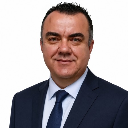 A man in a suit and tie smiles at the camera, representing our vocational education training expertise.